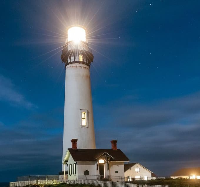 A lighthouse shining out over the sea at dusk